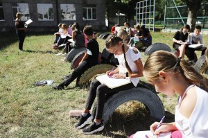 Діти сидять на шинах під час уроку географії у львівській школі. Клас облаштували на спортивному майданчику під час спалаху коронавірусної хвороби Covid-19