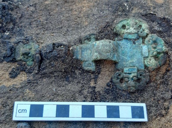 Хрестоподібна брошка, знайдена у похованні дорослої жінки. Імовірно, члени общини християнізувалися. 