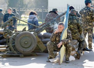 Український військовий тримає синьо-жовтий прапор і курить. Його базу оточили російські війська. Висунули ультиматум здатися. 22 березня 2014 року, Бельбек, Крим