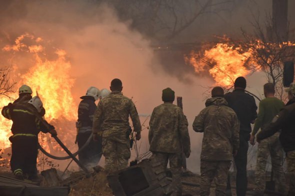 Военные и пожарные наблюдают за огнем, который перекинулся на дома в одном из сел Луганской области