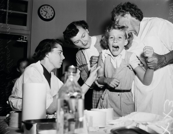 Лікар і медсестра вводять вакцину від поліомієліту першокласниці Тібор Фукс в американському Лос-Анджелесі 10 жовтня 1955-го. Того року щеплення від недуги отримали 57 млн жителів США. Так долали епідемію, що почалася після Другої світової війни. Хворобу спричиняла гостра вірусна інфекція, яка вражала нервову систему. Найвразливішими до неї були діти. У 40% розвивався параліч, десята частина гинули від дихальної недостатності. Вакцину розробив 41-річний Джонас Солк. Його називали чарівником, який врятував дитинство