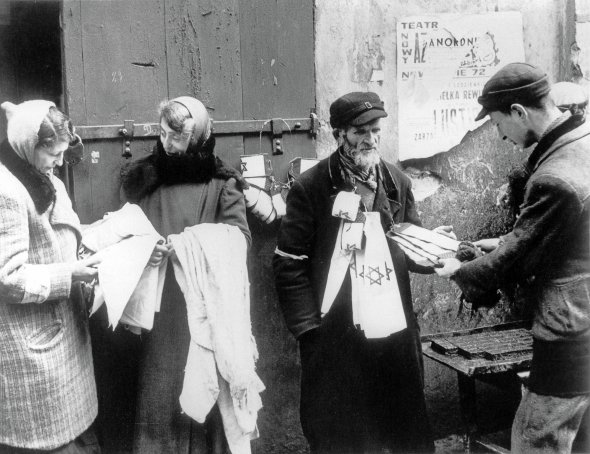 Чоловік продає на вулицях Варшавського гетто білі нарукавні пов'язки з блакитною зіркою Давида, 1941 рік. Німці змушували носити такі всіх євреїв