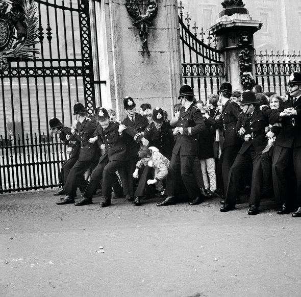 Поліцейські утримують фанів ліверпульського гурту The Beatles біля воріт Букінгемського палацу в Лондоні, 26 жовтня 1965-го. Тоді кожного з музикантів – Пола Маккартні, Рінго Старра, Джона Леннона і Джорджа Гаррісона – ”за вагомий внесок у справу процвітання Великої Британії” нагородили Орденом імперії. Через чотири роки Джон Леннон повернув свій королеві – на знак протесту проти воєн у світі