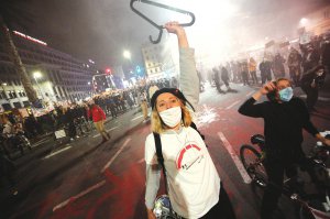 Жінка тримає вішалку для одягу — символ нелегальних абортів ­— під час протестів проти заборони переривання вагітності в польській столиці Варшаві 26 жовтня. Люди перекривали дороги. Влада біля церков виставила поліцейську охорону